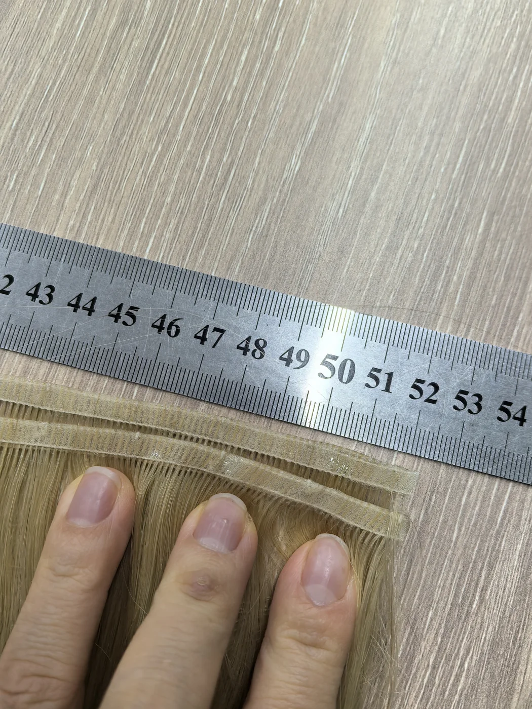 Checking a hairpiece measurement against a ruler.